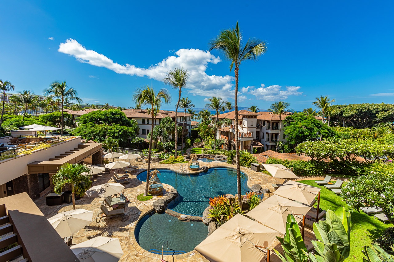 Palm-studded courtyard with sparkling pool and sun loungers, set against lush tropical landscaping and ocean views. An inviting oasis where your Hawaiian getaway begins.