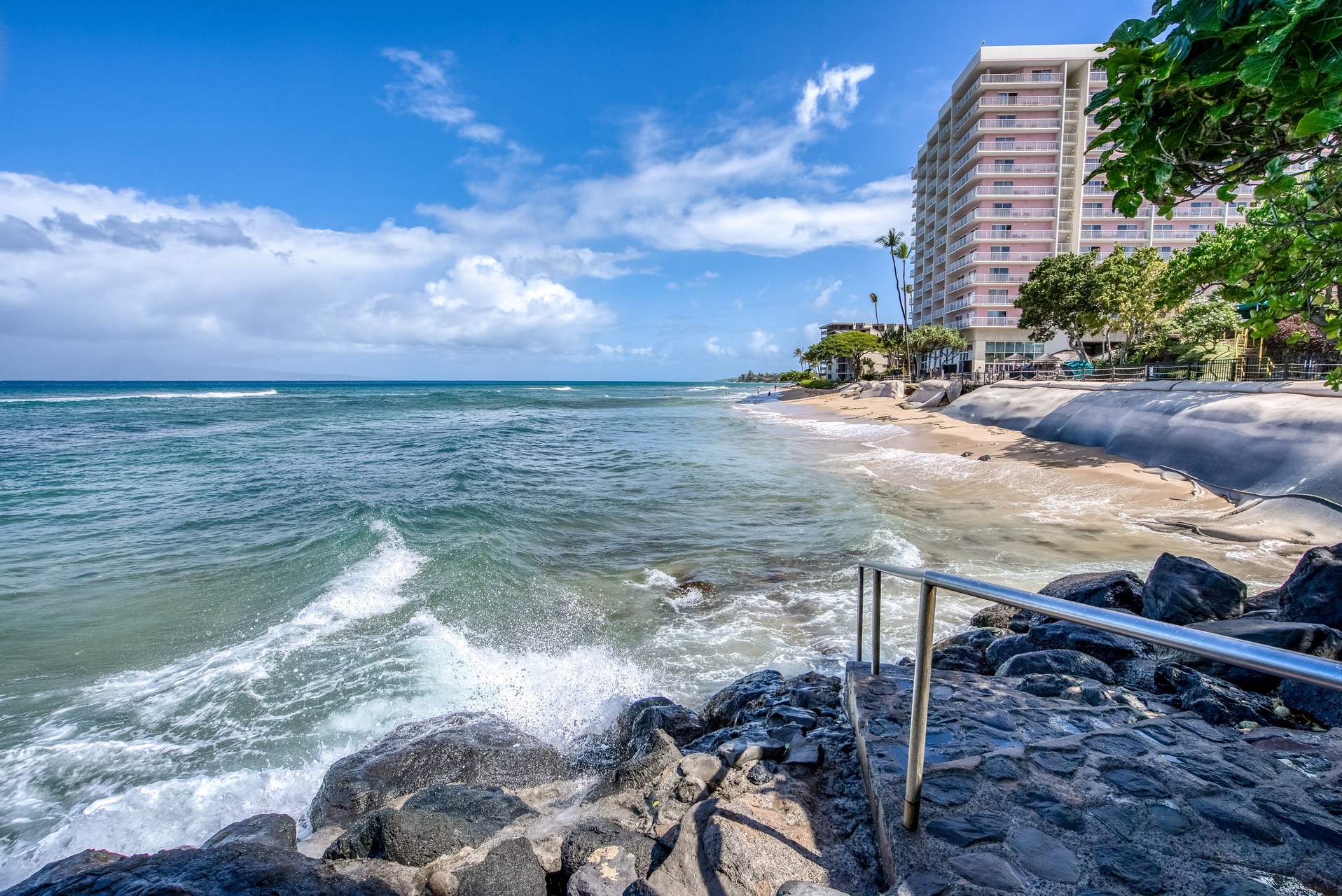 A stunning beachfront location awaits. The property sits steps from the ocean, surrounded by swaying palms and tropical greenery.
