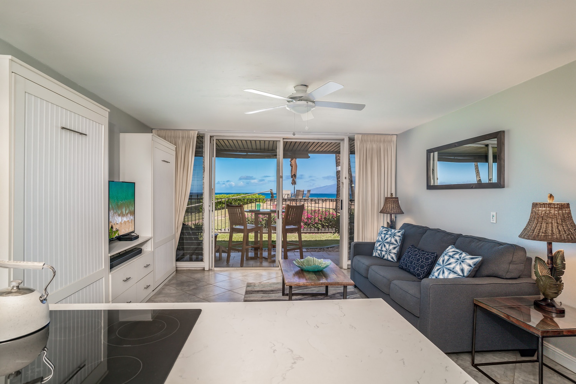 Relax in a bright, airy living space with doors opening to an ocean-view patio.