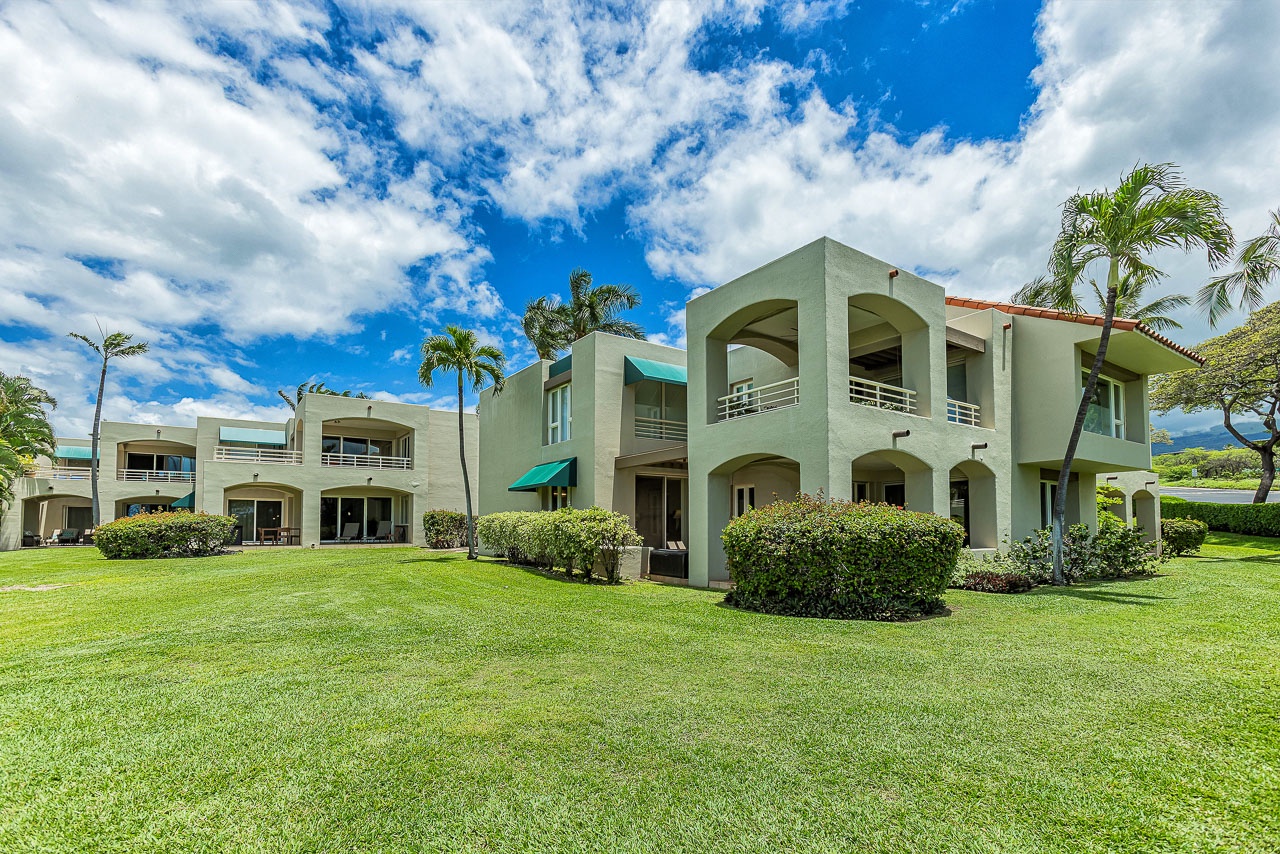 Modern tropical architecture framed by palm trees and lush green lawns under bright blue skies, showcasing the property's inviting exterior and resort-style setting.