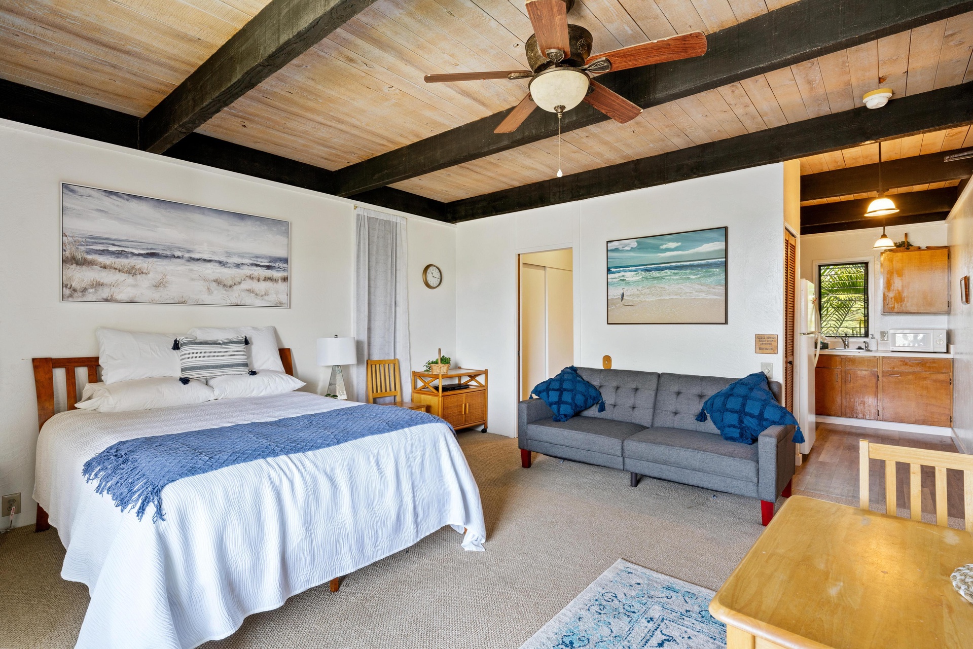 Relax in your bright, coastal-inspired suite with vaulted wood ceilings, a cozy bed, comfortable sofa, and coastal artwork that brings beachy vibes indoors.