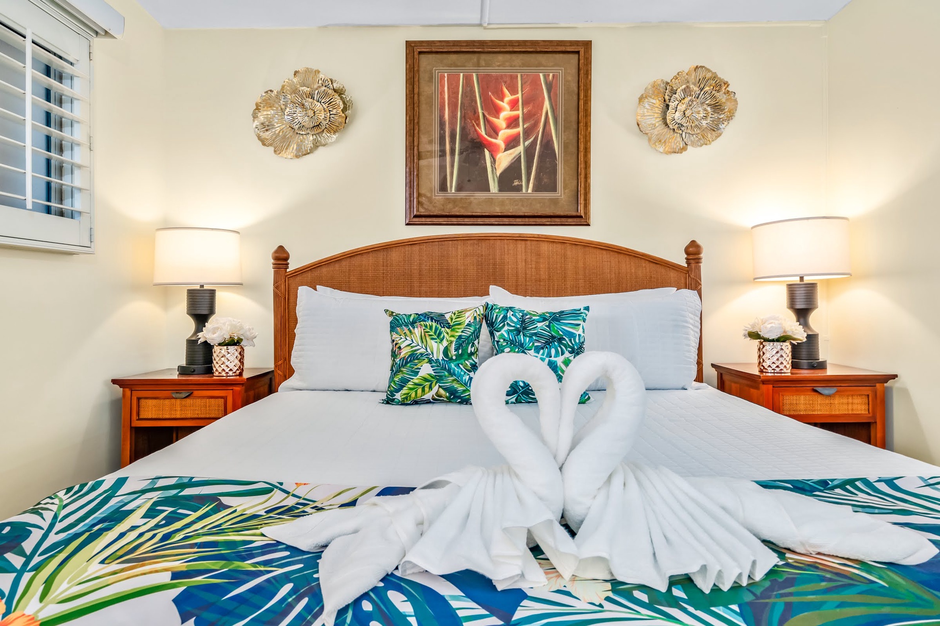 Sink into crisp white linens and tropical vibes as warm bedside lamps cast a gentle glow over your island-inspired sanctuary, complete with charming towel art to welcome you.