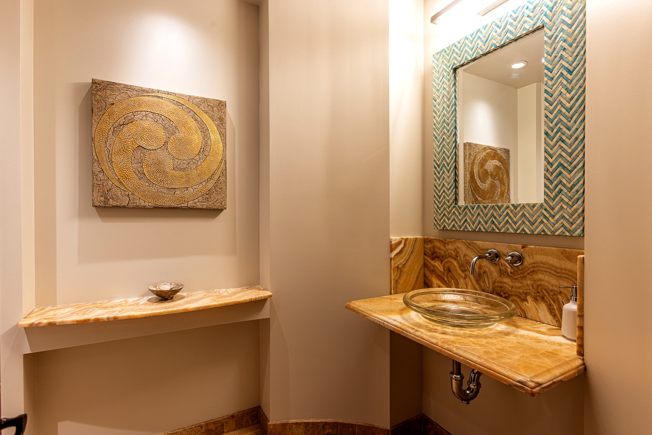 Your private half-bath features a unique glass vessel sink atop a beautiful live-edge wood counter, accented by artisan tile work and warm wood tones throughout.