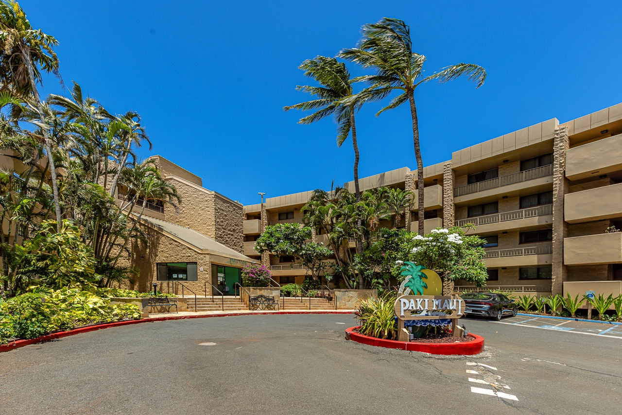 The property entrance features tropical landscaping, swaying palms, and convenient parking that welcomes you to your Hawaiian getaway.