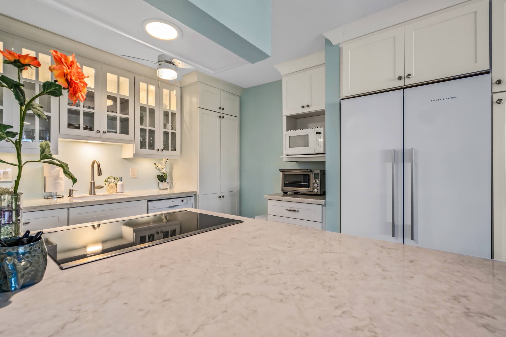 Picture yourself cooking in this elegant kitchen, where soft blue walls meet sleek marble counters and bright white cabinetry creates a calming, chef-ready space for your stay.