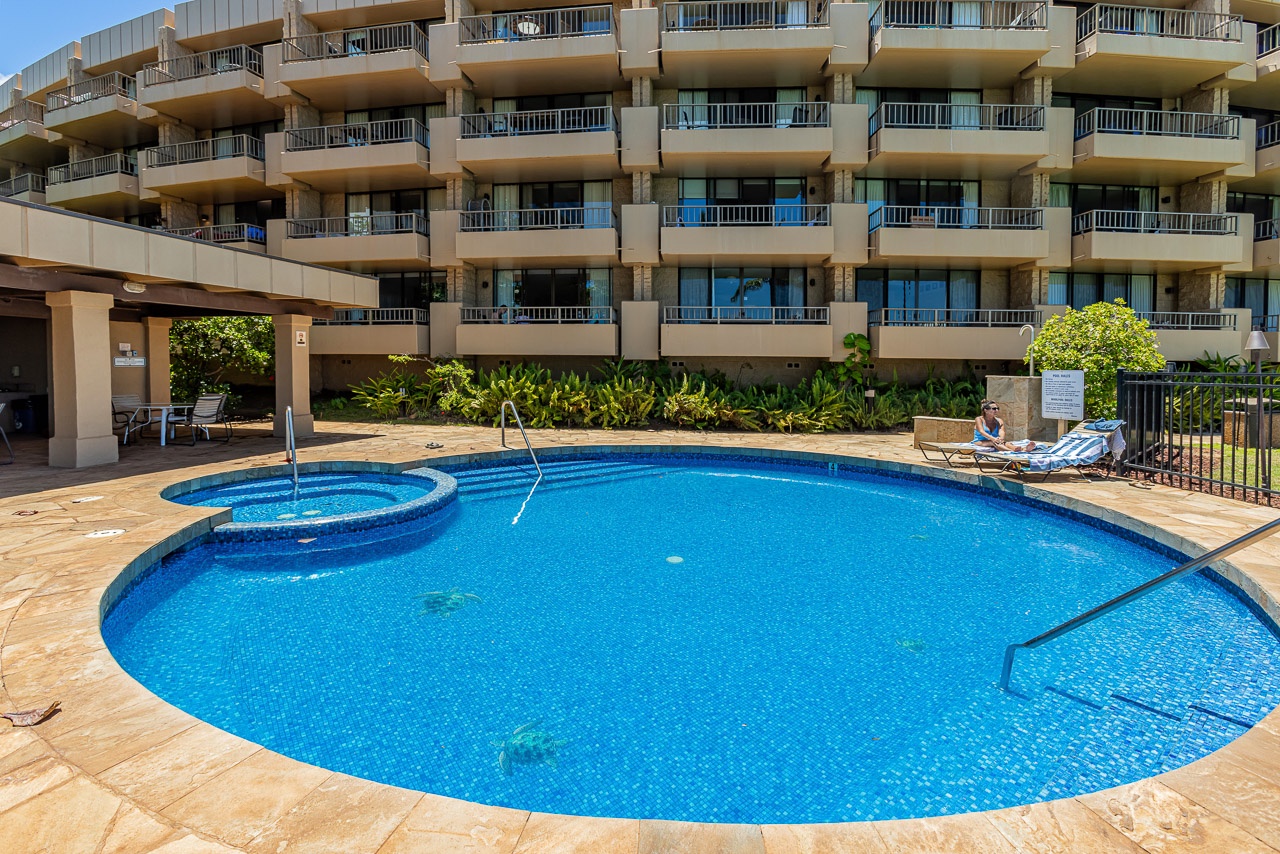 A multi-level property featuring tiered balconies, lush tropical landscaping, and an inviting curved pool with attached spa, providing a resort-style atmosphere for your stay.