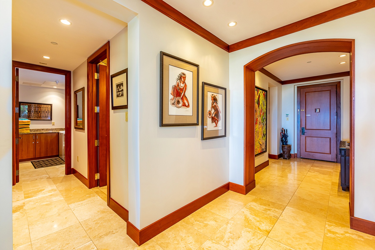 Step into your private sanctuary through gleaming travertine floors and rich mahogany archways. Thoughtfully curated island-inspired artwork and warm wood accents set the tone for a tropical escape that feels both elegant and welcoming.