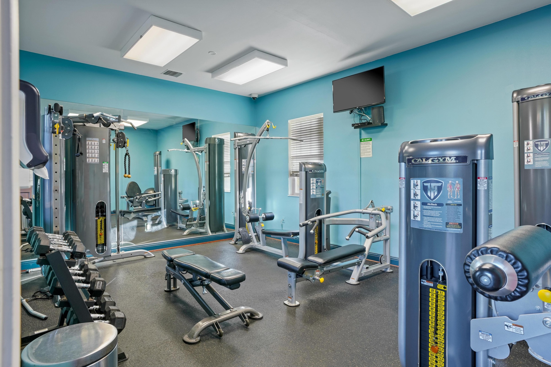 Your fully equipped fitness center features professional-grade equipment for strength training and cardio, all bathed in energizing natural light.