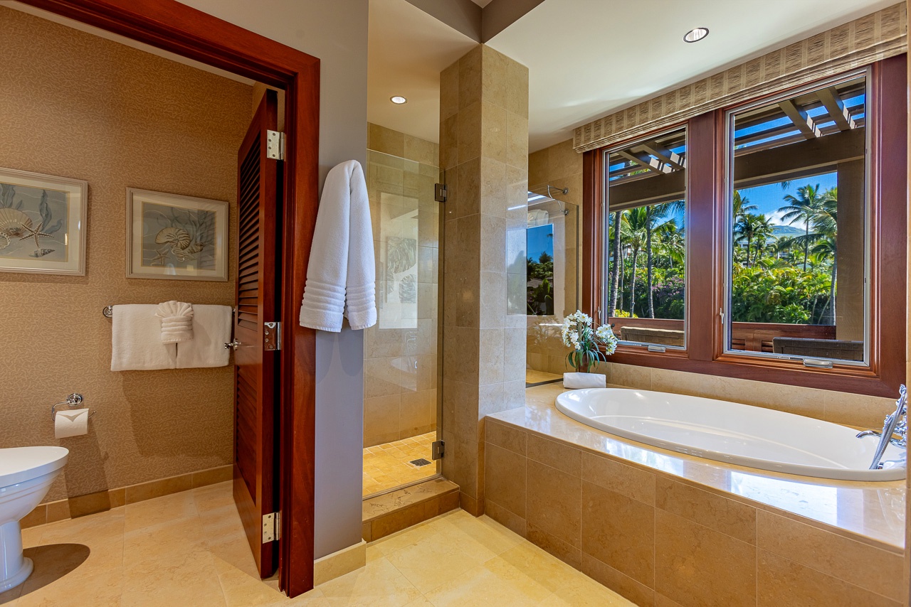 Your private spa-like bathroom invites you to unwind in the soaking tub while gazing out at lush tropical palms through beautiful wood-framed windows. Wrap yourself in plush towels and enjoy the serene garden views.