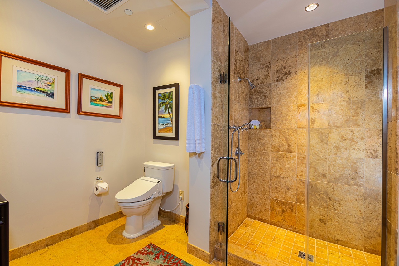 Your private bathroom features a spacious walk-in shower with elegant travertine walls and fresh towels waiting for you.