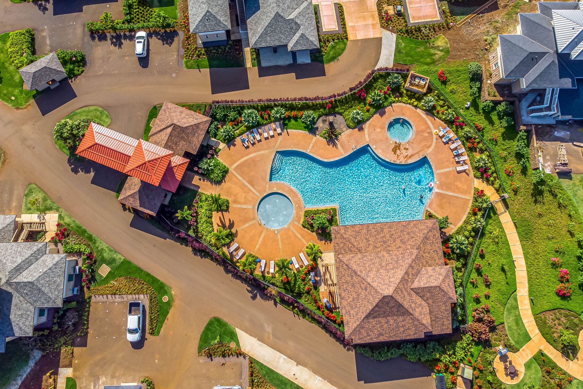 Aerial view showcasing the resort's stunning curved pool complex with hot tub, surrounded by tropical landscaping and residential buildings.