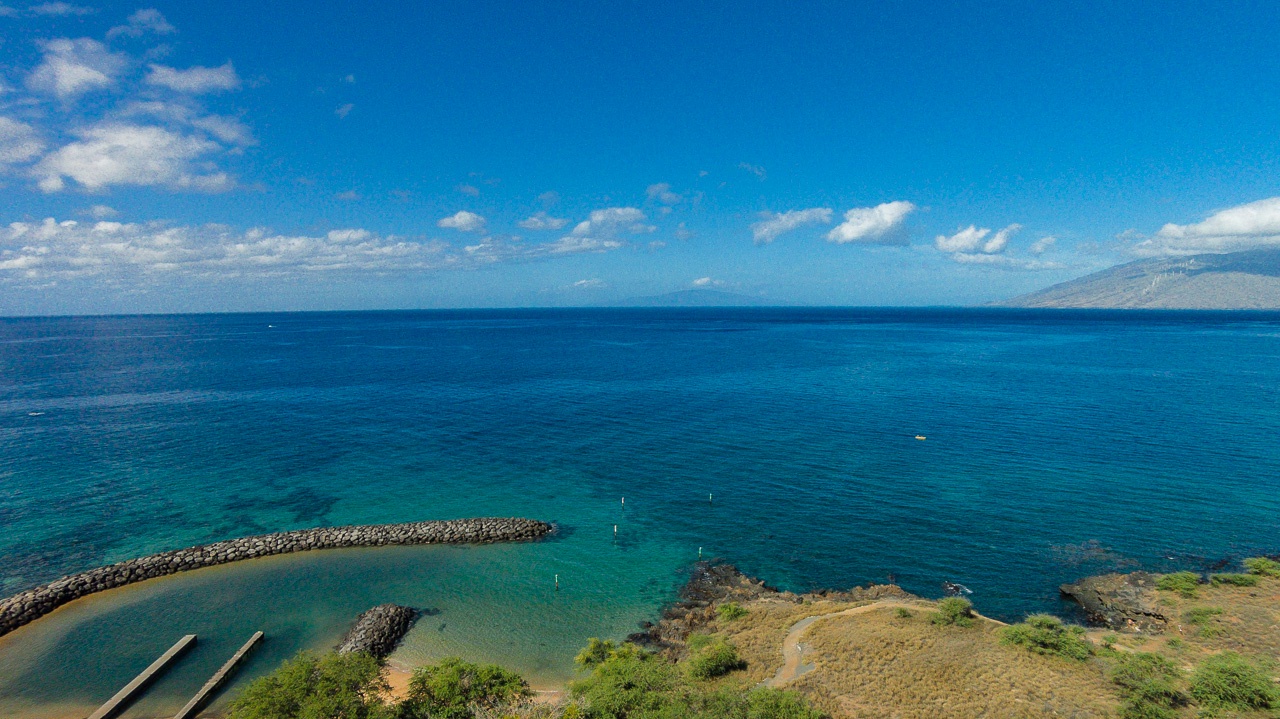 Stunning aerial view of pristine coastline with turquoise waters and small harbor, showcasing the natural beauty of the surrounding area.
