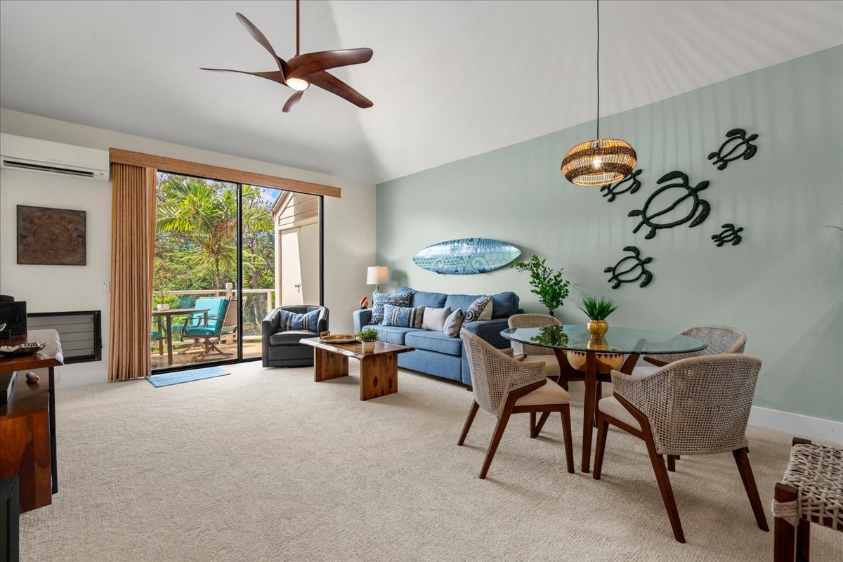 Relax in your airy living and dining space featuring coastal-inspired décor, ceiling fan, AC, and balcony access with tropical garden views perfect for your morning coffee.