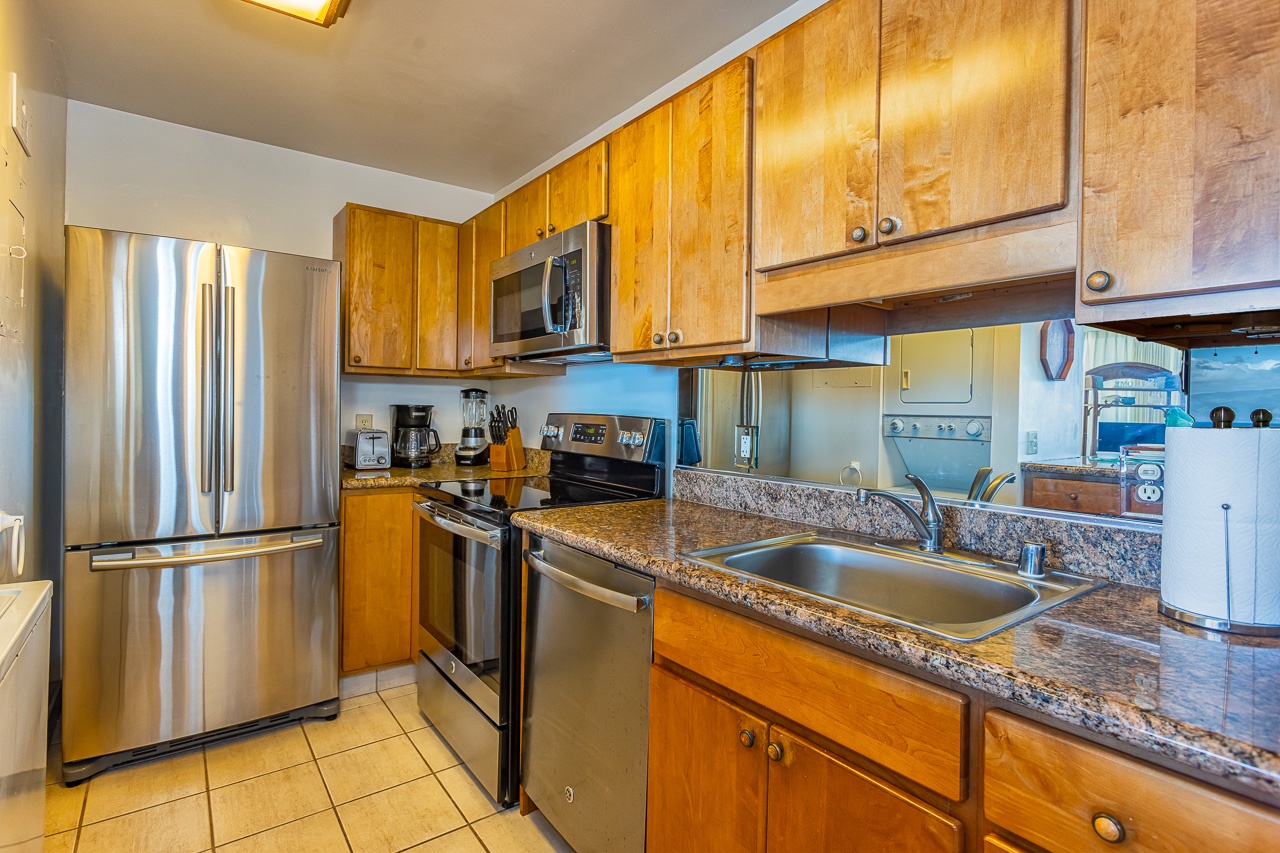 Step into this well-equipped kitchen where golden wood cabinetry and speckled granite countertops create a warm, inviting space for preparing your favorite meals during your stay.