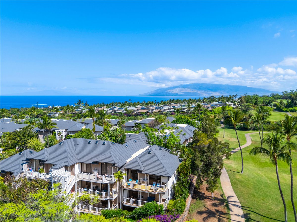 Scenic tropical property overlooking lush golf course greens with ocean and mountain vistas, offering tranquil island surroundings and natural beauty.