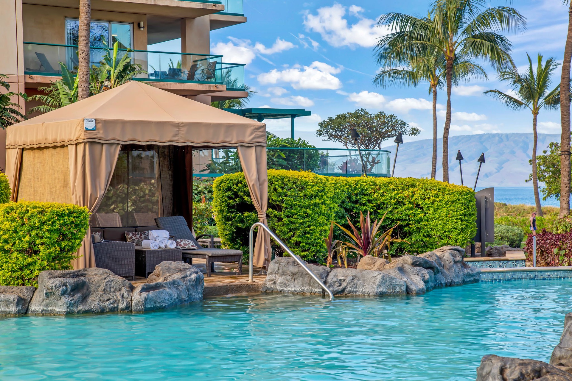 Lounge in comfort beneath a private cabana while the sounds of cascading waterfalls create a peaceful tropical ambiance.