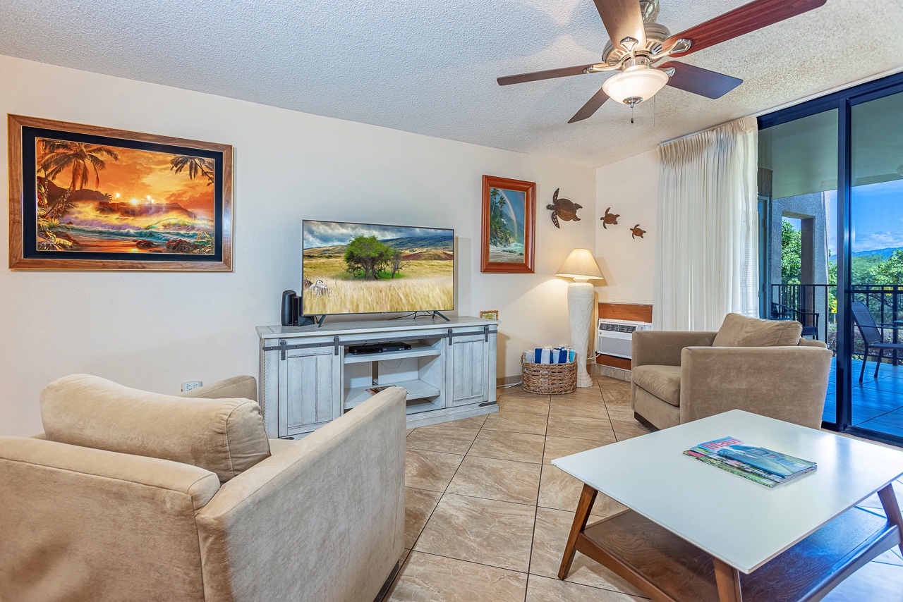 Settle into your comfortable living room with coastal decor and ceiling fan cooling, where sliding doors open to your private balcony and tropical views beyond.