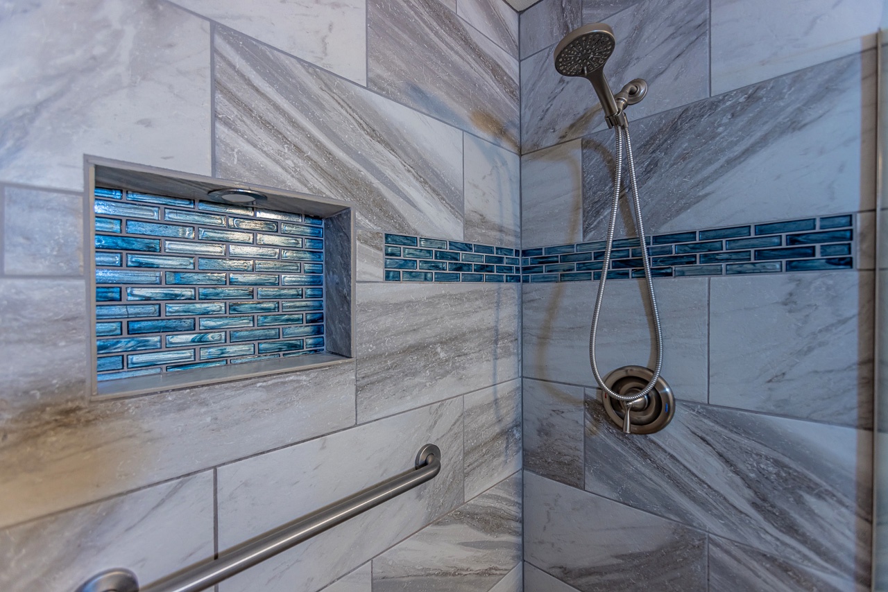 Step into your spa-like shower, where soft gray marble and a vibrant blue tile accent create a calming retreat. The handheld showerhead and convenient niche make your morning routine effortless.