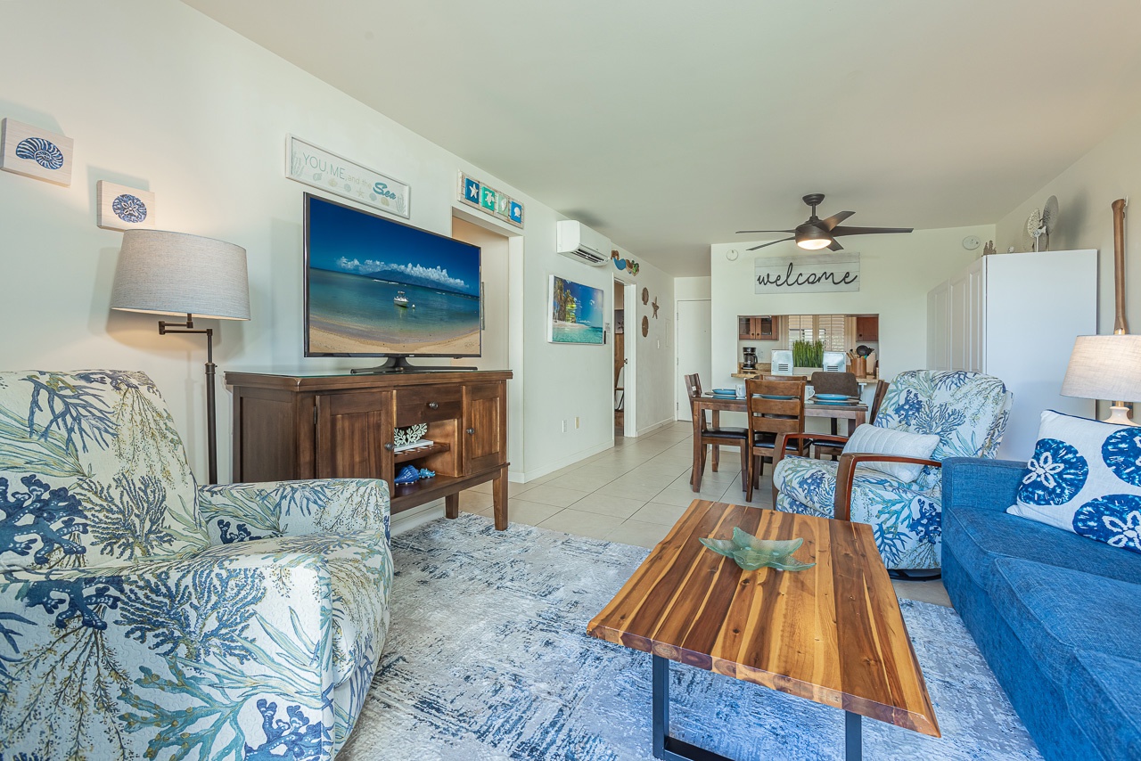 Relax in your coastal-inspired living room with ocean-themed decor, flat-screen TV, and open layout connecting to the kitchen.
