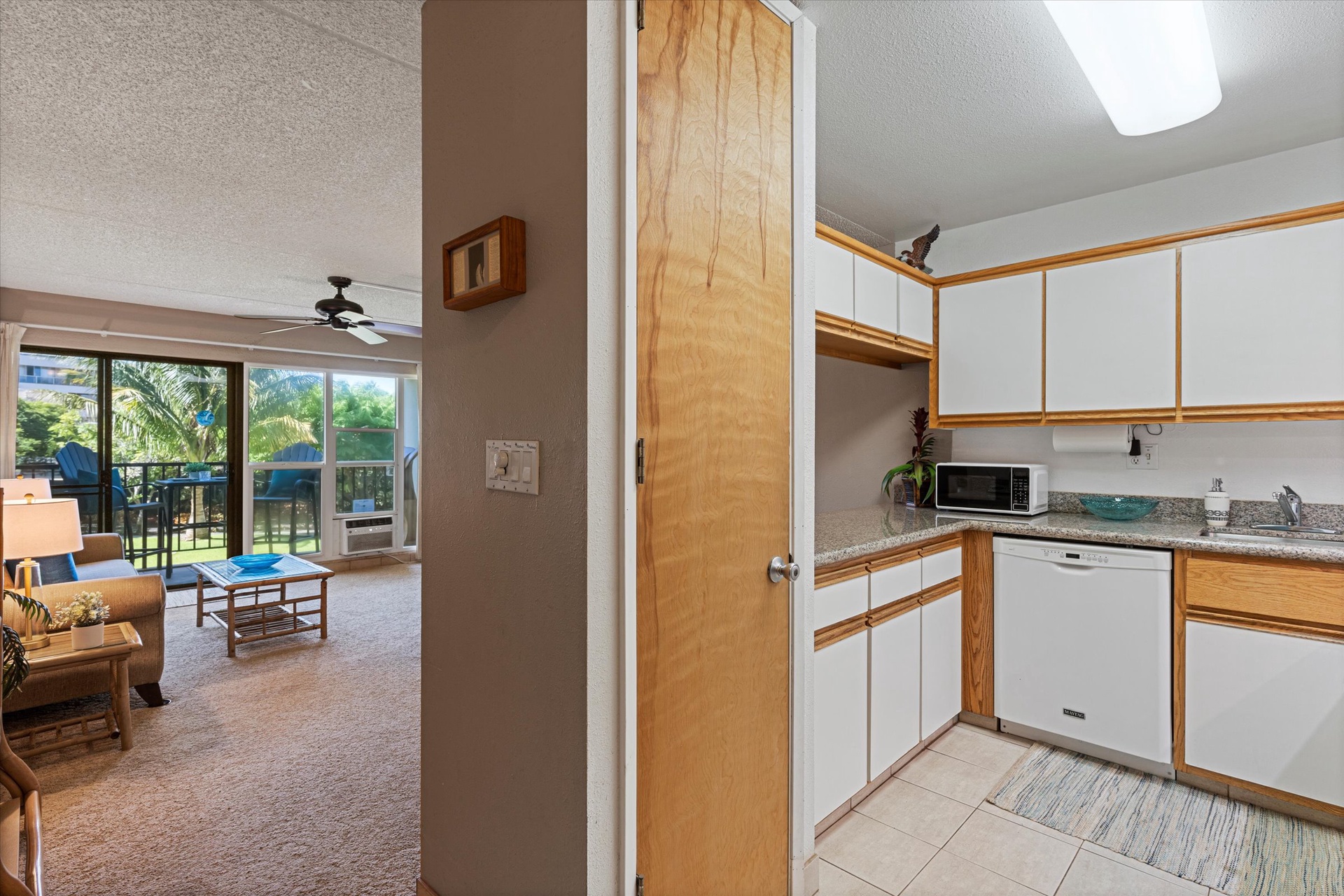 Your well-equipped kitchen flows seamlessly into a bright living area, where palm trees sway just beyond the balcony doors, inviting you to unwind in tropical comfort.