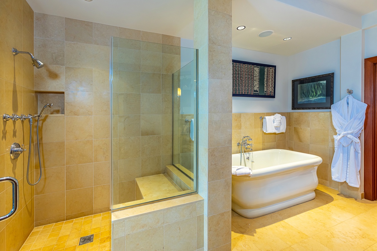 Step into your private spa retreat: a spacious bathroom with a glass-enclosed shower, elegant soaking tub, and plush robe waiting just for you.