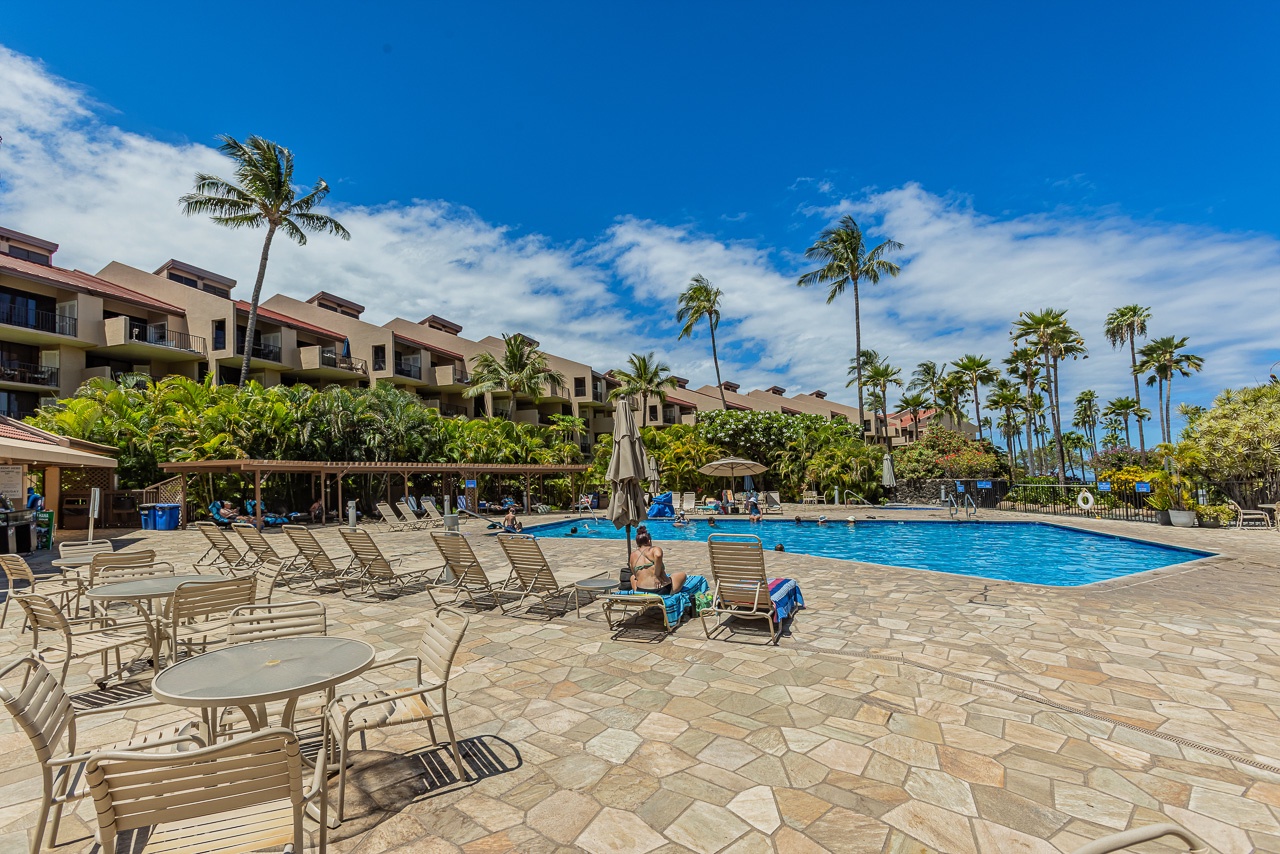 An inviting beachfront retreat surrounded by swaying palms and tropical gardens, with a pristine pool and spacious lounging areas perfect for soaking up the Hawaiian sunshine.