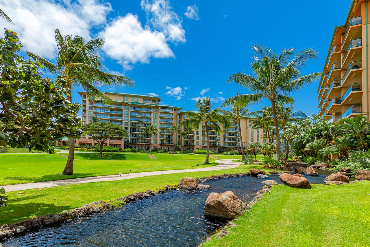 A tropical resort setting surrounded by lush palm trees, manicured lawns, and tranquil water features creates an inviting Hawaiian atmosphere perfect for your island getaway.