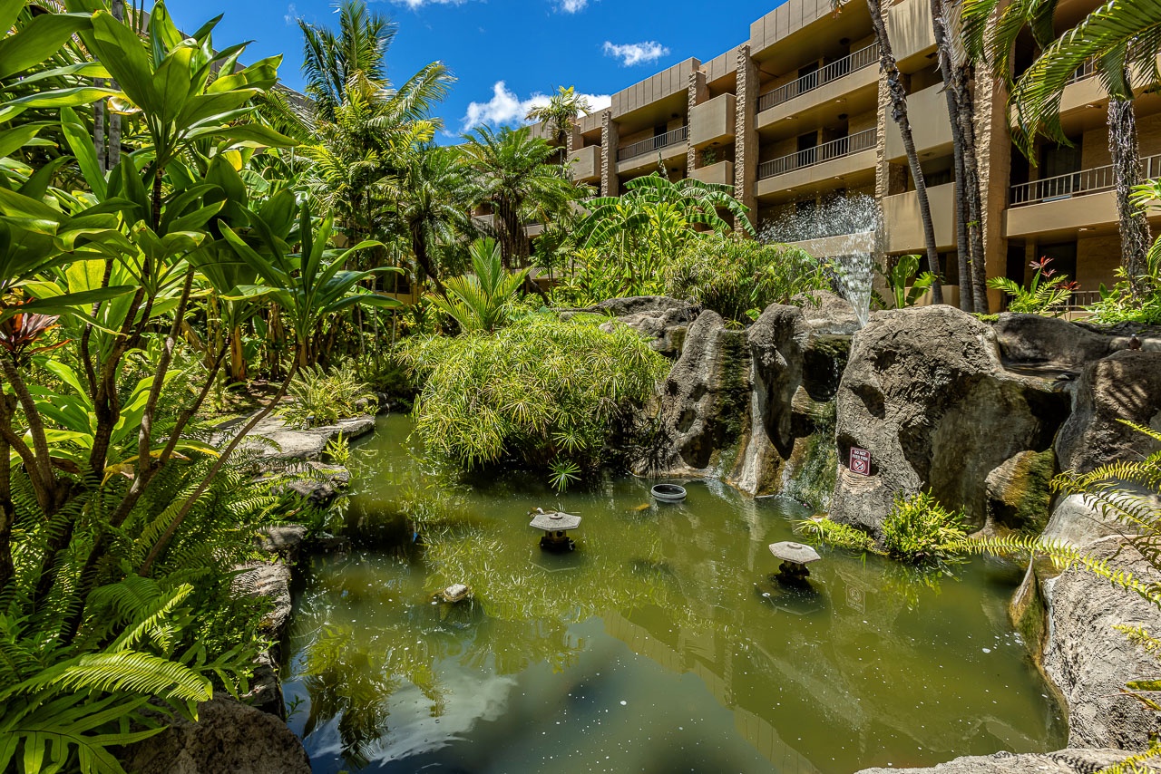 A tranquil koi pond surrounded by lush tropical gardens creates a peaceful retreat at this Hawaiian property, with modern balconies overlooking the serene natural setting.