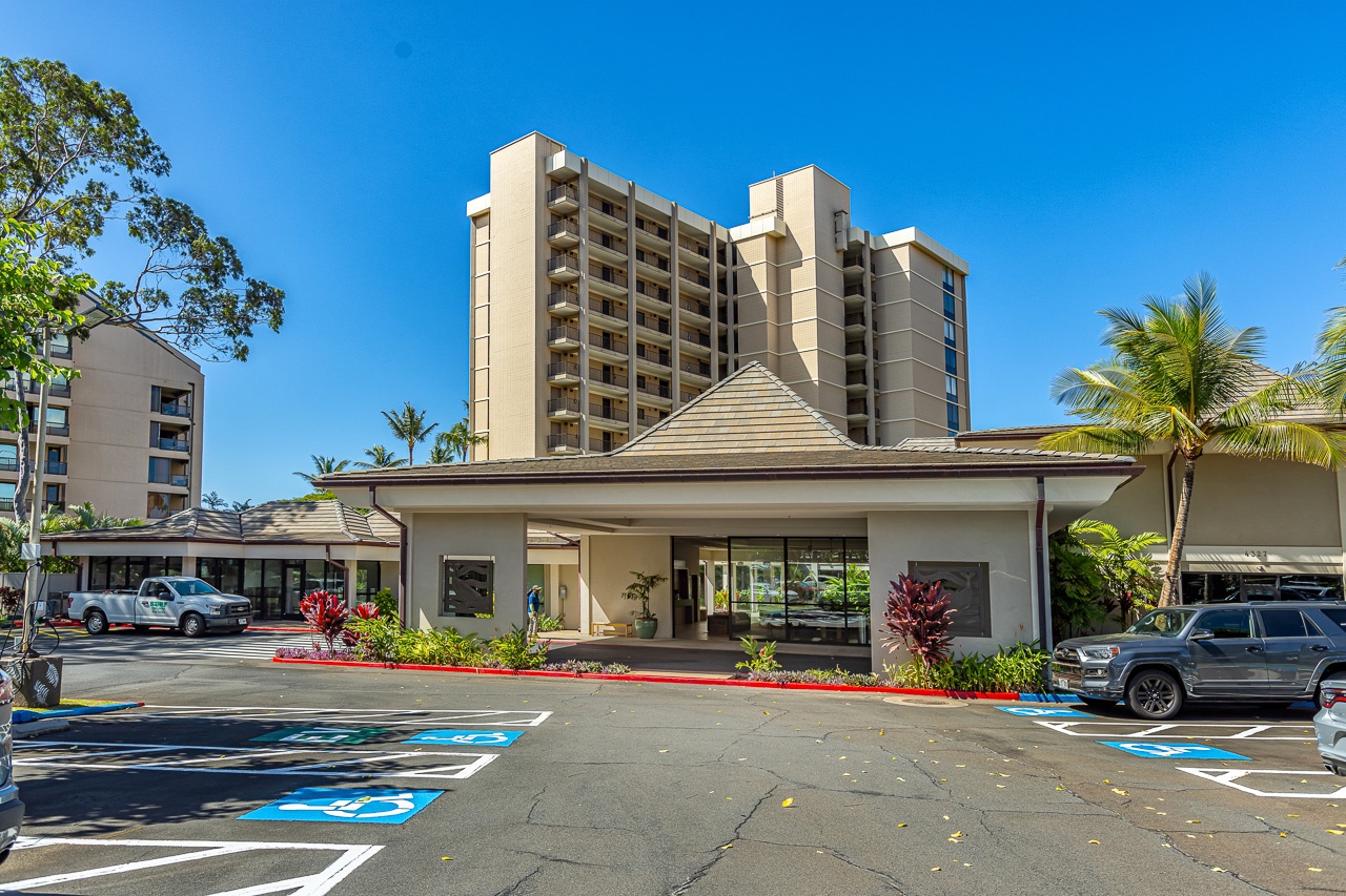 A welcoming resort complex set against vibrant blue skies, framed by swaying palms and lush tropical landscaping—this marks the beginning of your Hawaiian getaway.