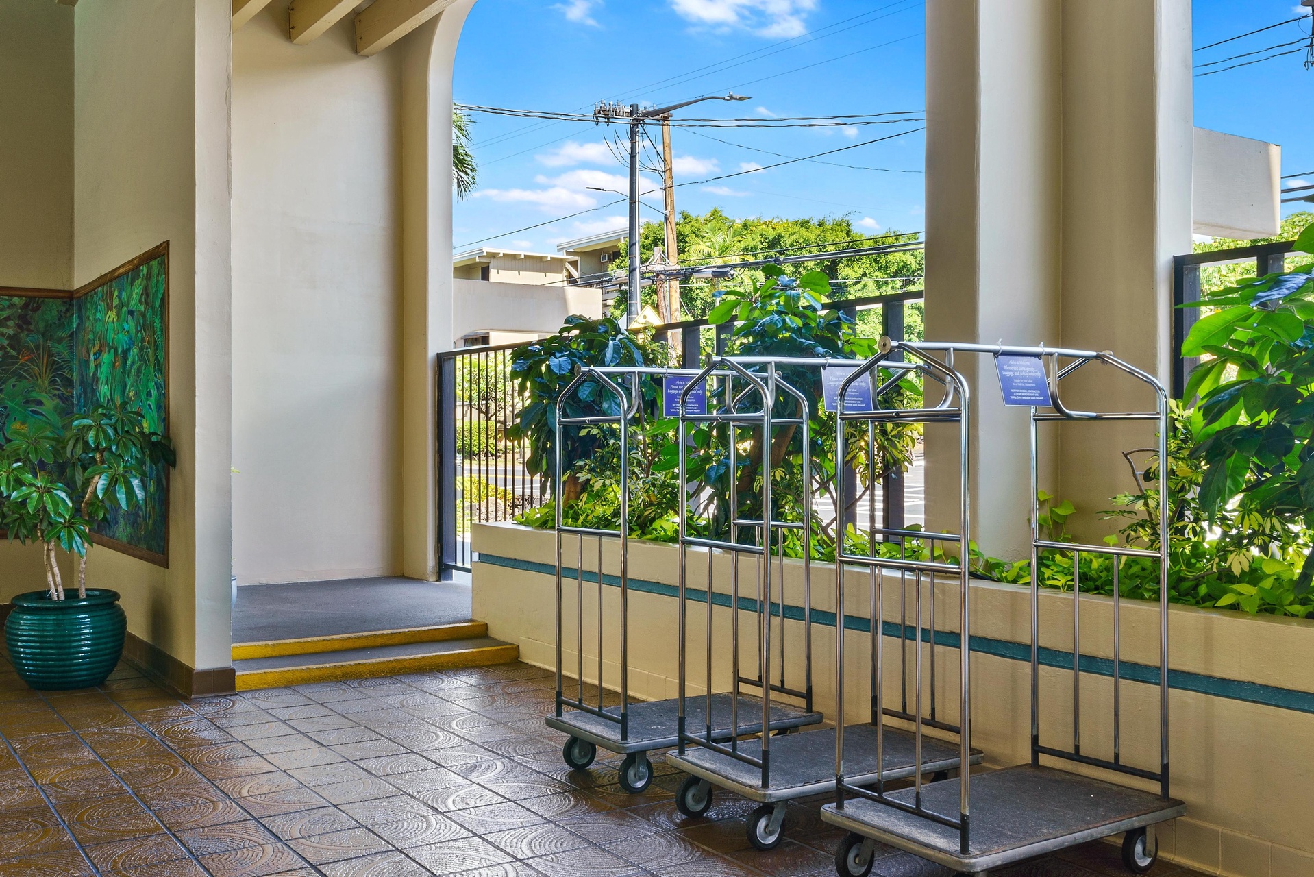 The property's welcoming entrance features lush tropical greenery and convenient luggage cart access for a smooth arrival experience.