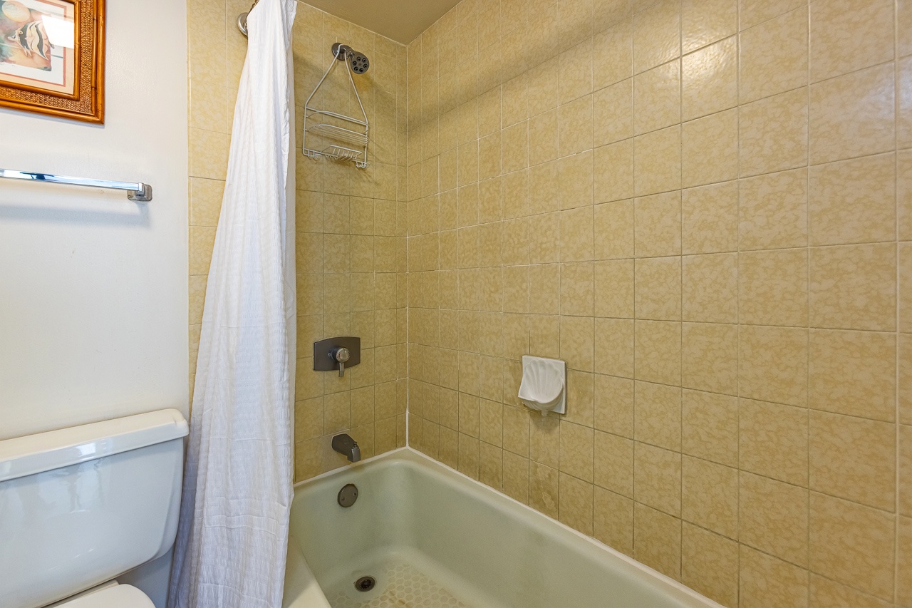 Your private bathroom features a full tub-shower combo with warm beige tile and all the essentials, including a plush shower curtain for added comfort.