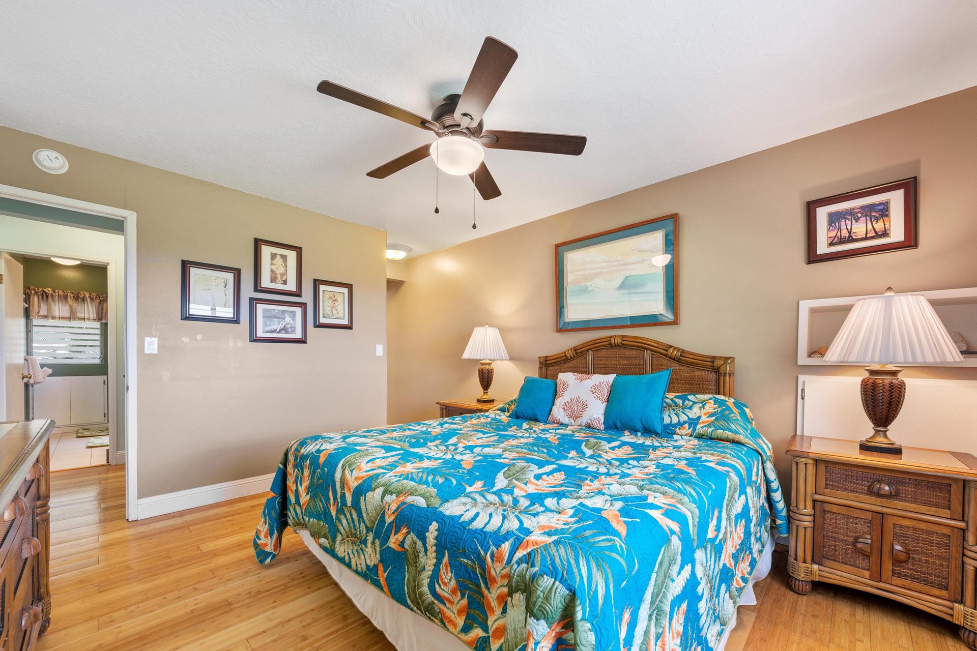 Drift off in your tropical-themed bedroom with bright island bedding, warm wood floors, and a gentle ceiling fan overhead.