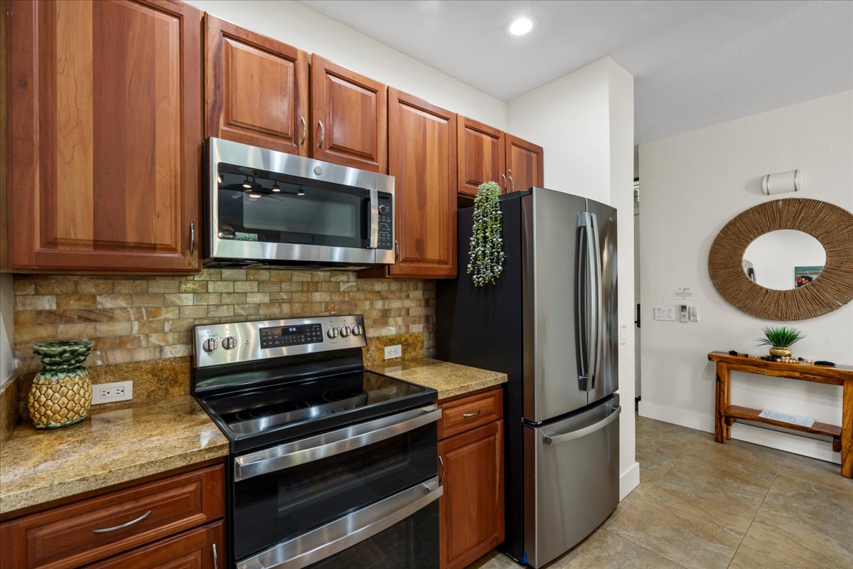 You'll love this fully equipped kitchen with modern stainless steel appliances, granite countertops, rich wood cabinetry, and tasteful tile backsplash—ready for cooking your favorite meals during your stay.