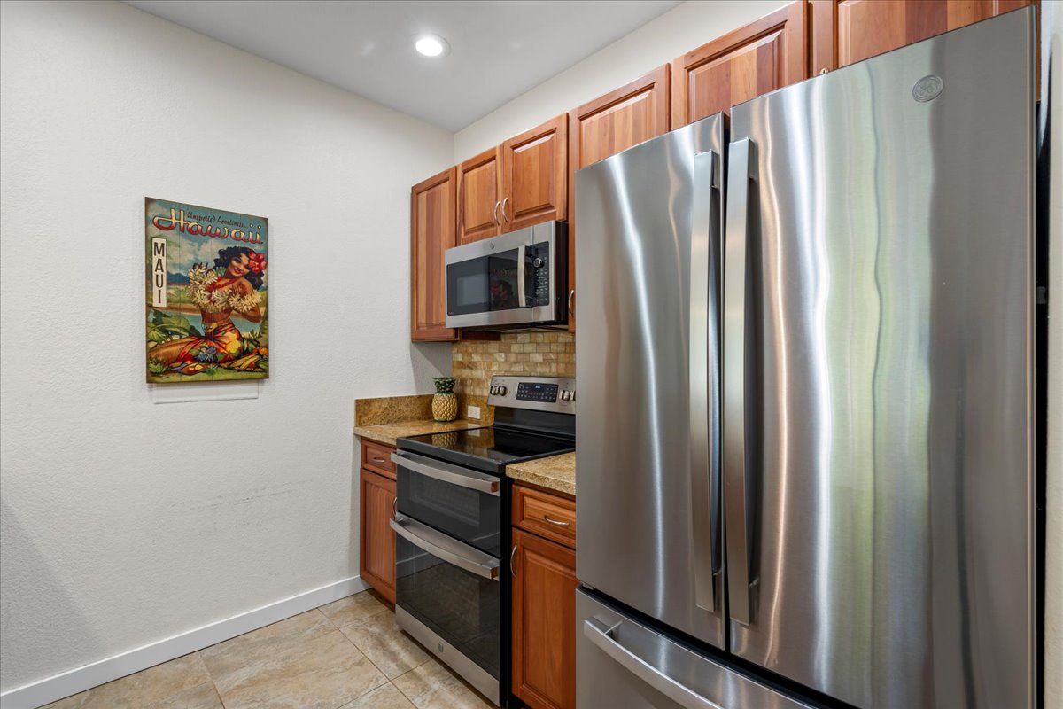 Your gourmet kitchen features gleaming stainless steel appliances, warm wood cabinetry, and granite countertops—perfectly equipped for preparing island-inspired meals during your Hawaiian escape.