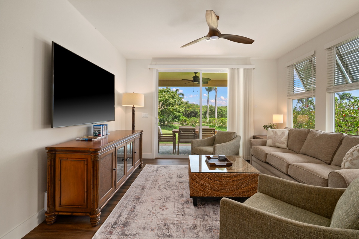 Unwind in your elegant living room with plush seating, entertainment center, and stunning views of lush tropical gardens through floor-to-ceiling windows.