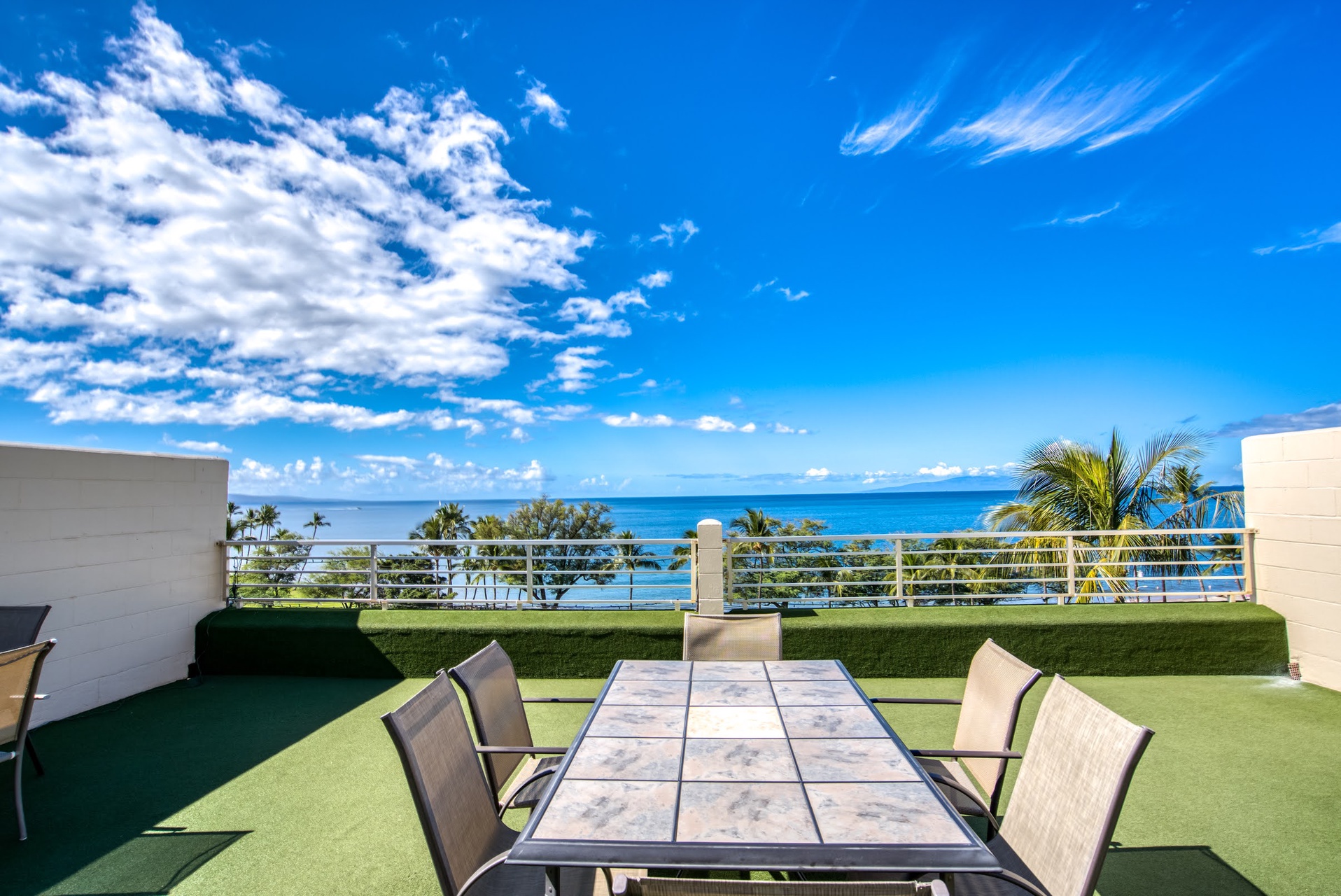 Ocean-view balcony terrace with tropical breezes, dining table for gatherings, and stunning blue-sky horizons over palm-fringed shores.