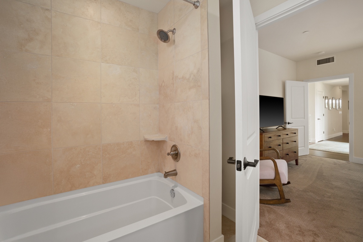 Your private bathroom features a relaxing soaking tub with elegant travertine tile walls and modern fixtures for your comfort.