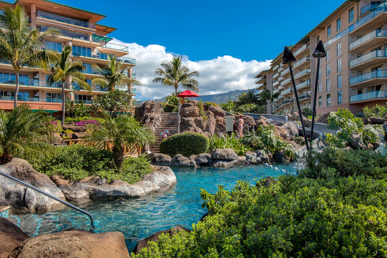 A tropical lagoon-style pool, with a waterslide, winds through lush landscaping creating a resort paradise.
