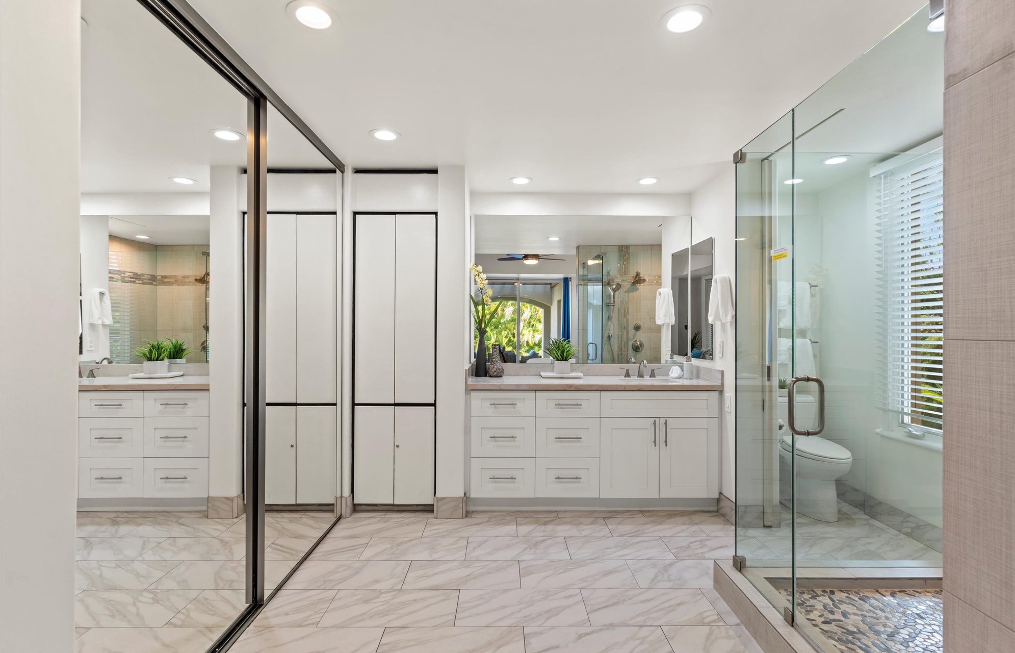 Your spa-like primary bathroom offers sleek white cabinetry, a spacious glass-enclosed shower, and bright recessed lighting. Elegant herringbone tile underfoot adds a refined touch to your private retreat.