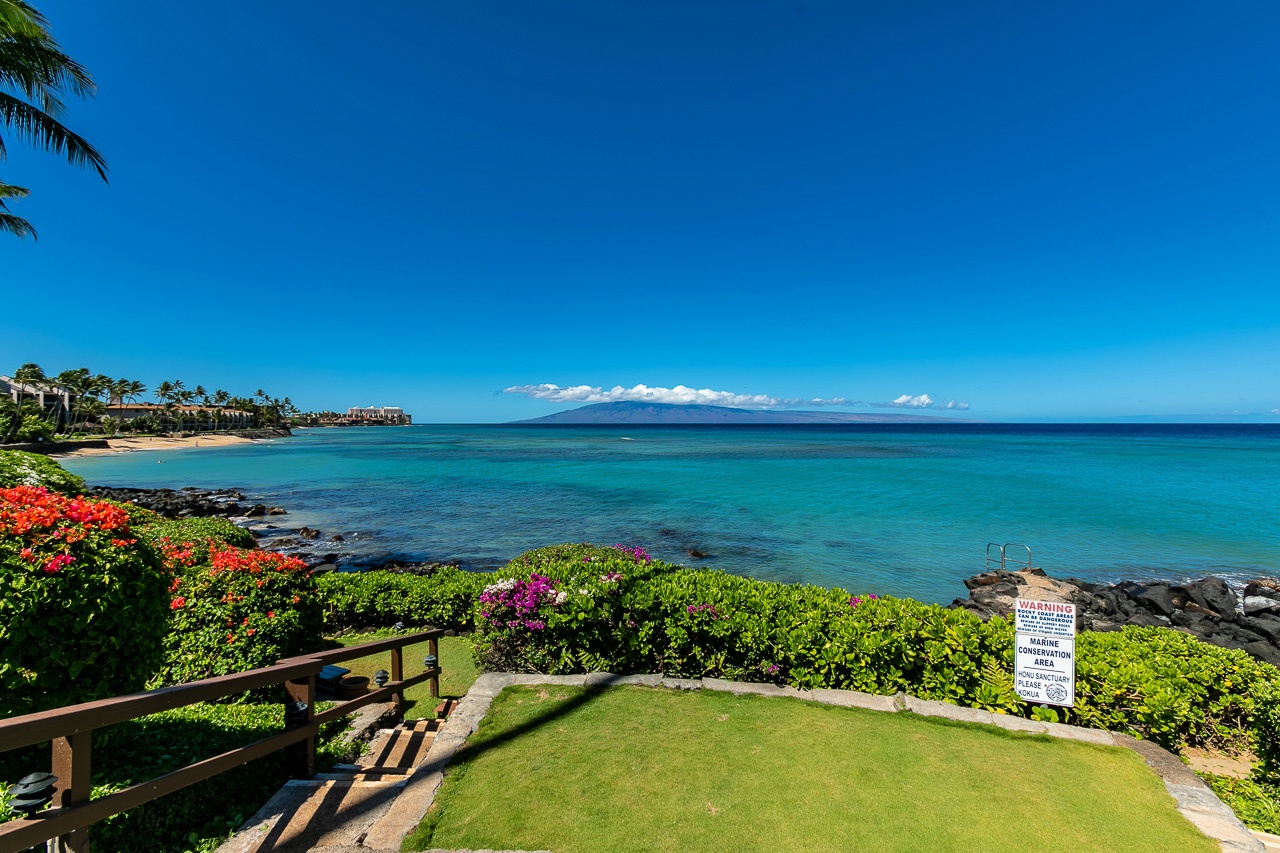 Stunning coastal location surrounded by vibrant tropical gardens and pristine turquoise waters, with a picturesque island visible on the horizon.