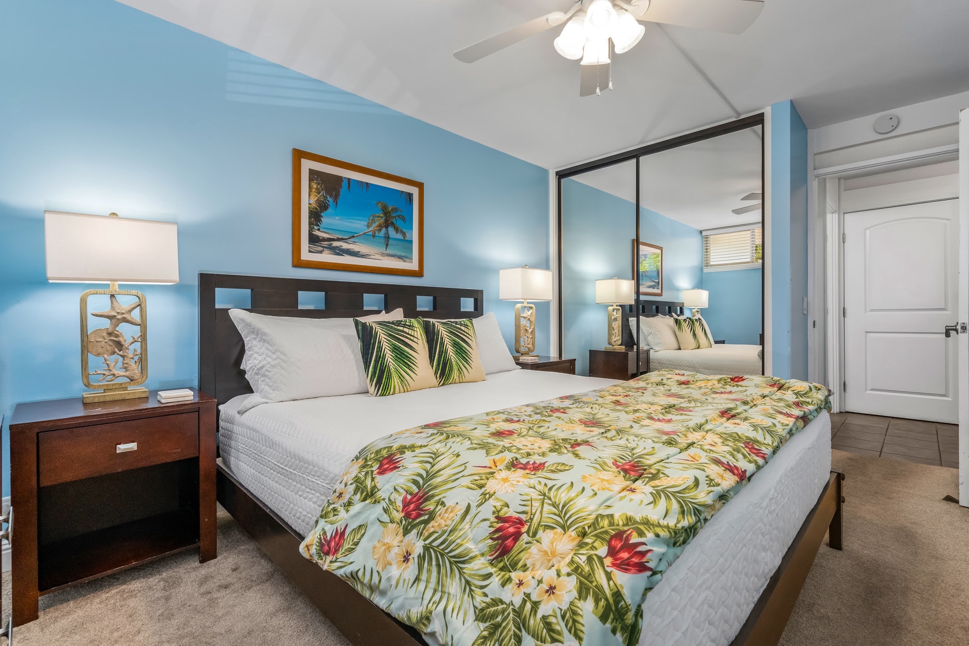 Sink into a plush bed dressed in tropical bedding, with calming blue walls and warm lighting creating your personal island retreat after a day of adventure.
