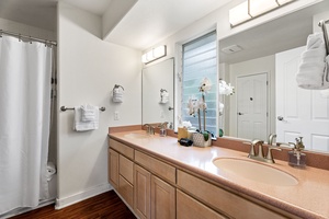 Your spacious bathroom features dual sinks, elegant countertops, and fresh orchids adding a spa-like touch to your morning routine.