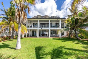 Grand rear view of the estate surrounded by swaying palms and mountain peaks.