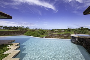 Infinity pool overlooks lush tropical landscape with golf course views and distant palm trees under brilliant blue skies.