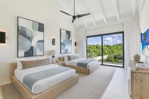 Enjoy the airy bedroom with two beds and a view of the lush landscape.