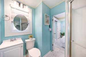 Cool blue and a round mirror make the hallway bath feel calm.