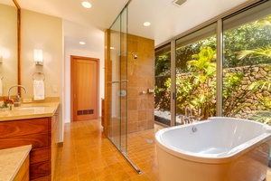 A glass-walled shower and tropical garden views turn this ensuite into a spa-like escape.