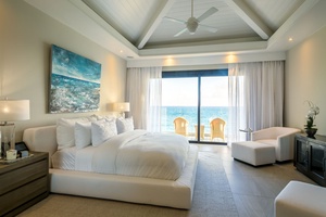 Wake up to stunning ocean views in this luxurious bedroom, featuring a plush bed.