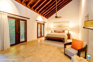 Cozy guest bedroom with seating area and high ceiling.