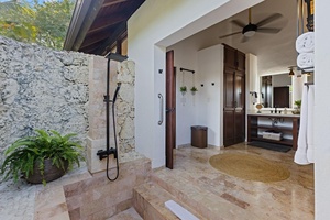 An inviting outdoor shower area with stone walls and a rain shower head.